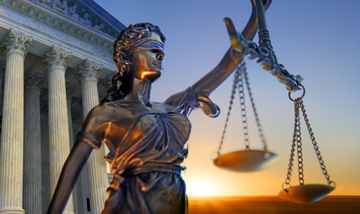 A statue of the blindfolded lady justice in front of the United States federal court building.