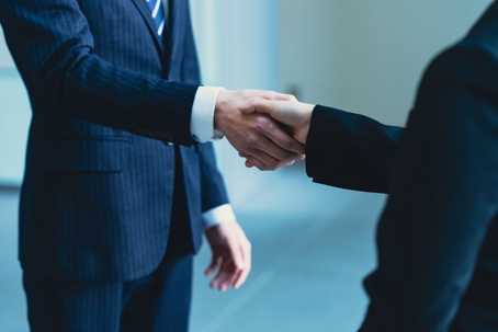 A business handshake between two professionals wearing suits. | Shellist Lazarz Slobin